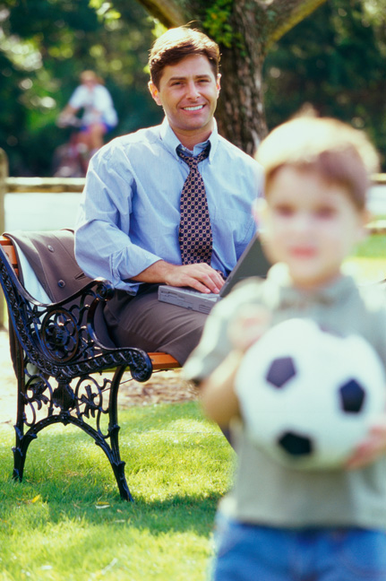 Smiling father watching son play soccer