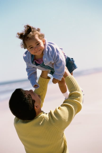 Daughter being lifted into the air by father on beach