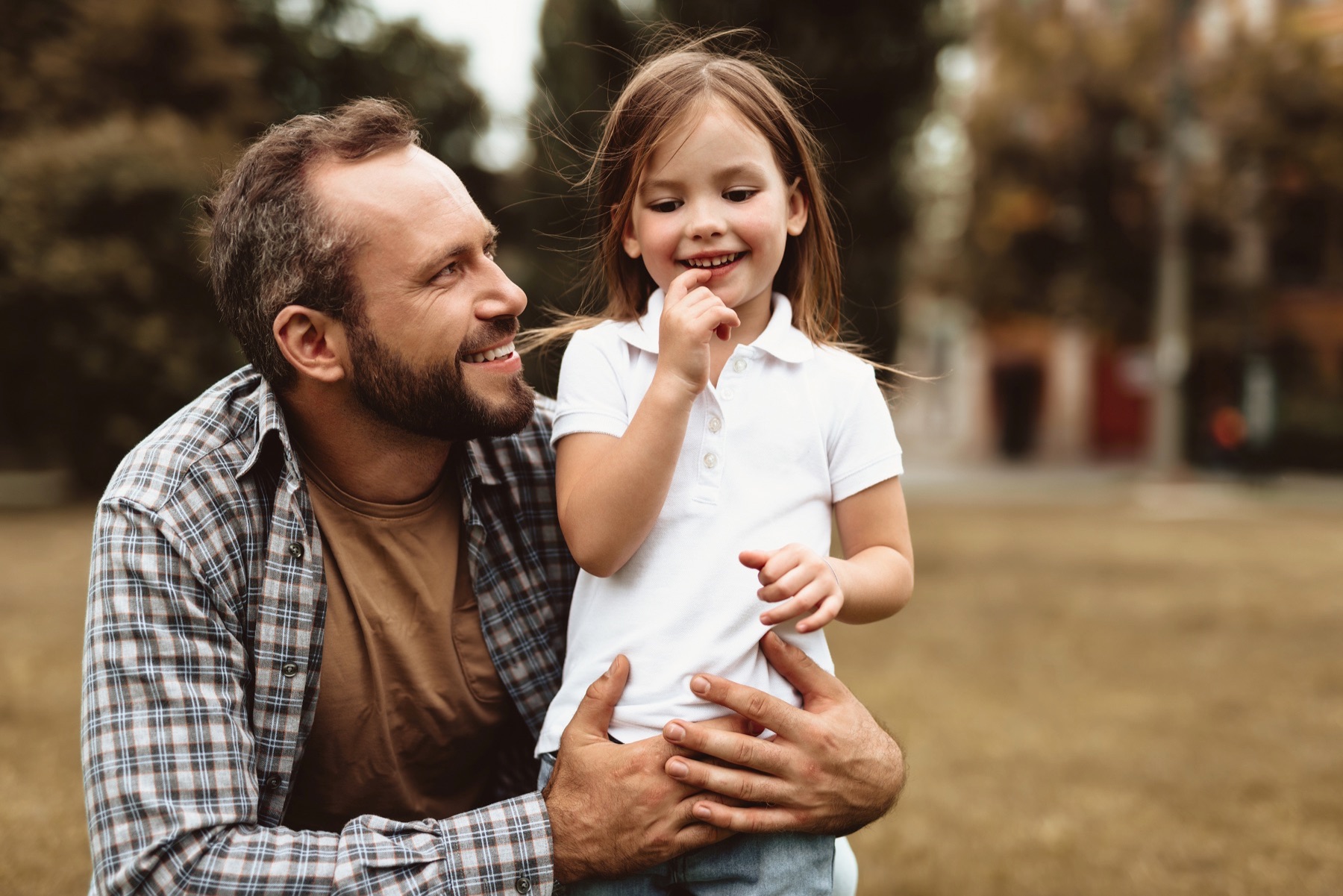 Father and daughter play together outside.