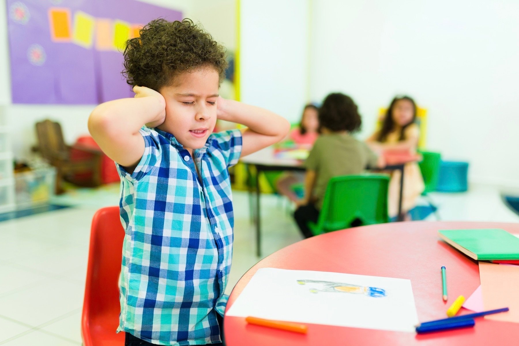 Little boy covering ears while overstimulated. 