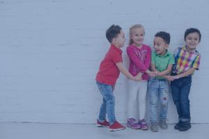 Four little kids hold hands while laughing.