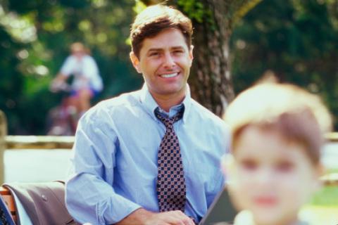 Smiling father watching son play soccer