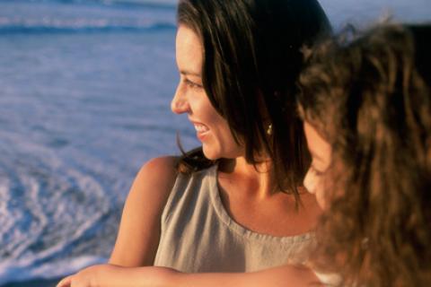 Mother holding daughter while looking at ocean