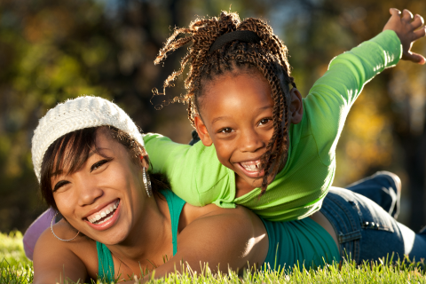 Mother and daughter playing outside in the grass on a sunny day