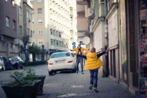 Son and father running toward each other for a hug on the street.