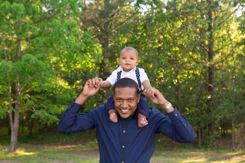 Father carries baby on shoulders outside