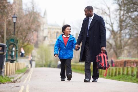 Father holds his sons hand while walking him to school