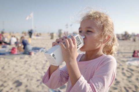 A young girl enjoys a cold water on the beach.