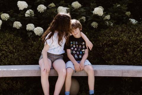 Two siblings sit together at the park.