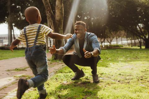 Young boy runs into his smiling father's arms on a clear spring day