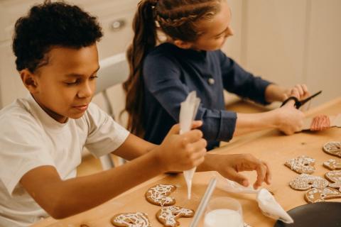 Two kids decorate cookies in the kitchen