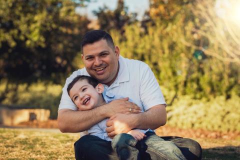 A father hugs his son on a sunny day in the park