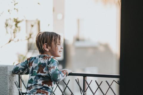 Little girl looks at her neighborhood from the balcony of her family's apartment.