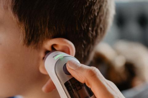 Parent takes the temperature of their child with an ear thermometer.