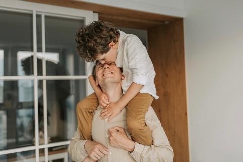 A father carries his son on his shoulders.