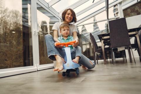 A mother and child ride a small bike together at home.