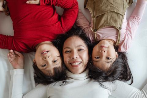 A woman and two children laying together.