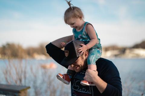 A man holds a young child on his shoulders during a walk.