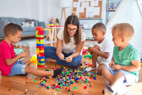 A group of young boys play with Legos with their female nanny.