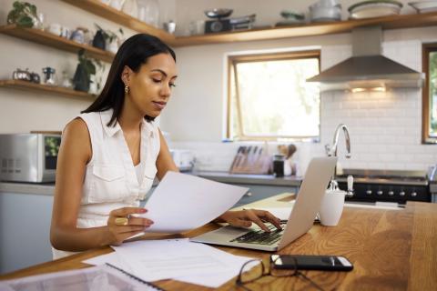 Woman on computer in kitchen. 