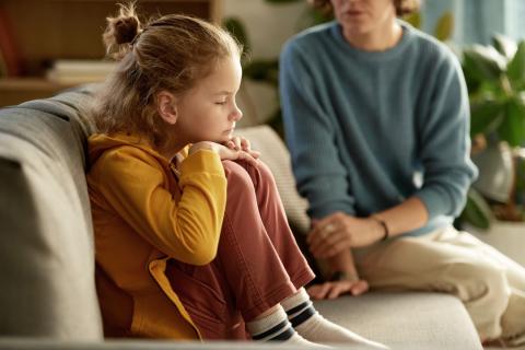 Boy sitting on couch not listening to his mom. 