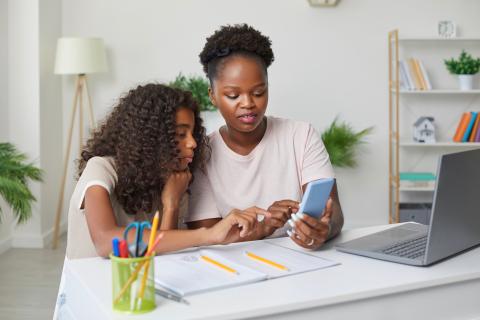 Mom showing her daughter something on her phone.