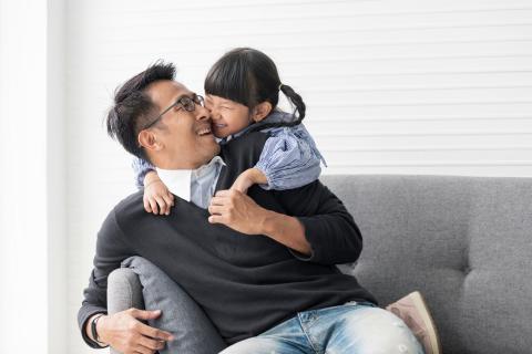 Daughter hugging her dad on couch.