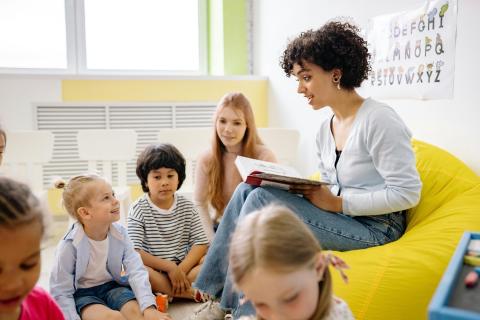 Group of kids listening to teacher during story time at school.