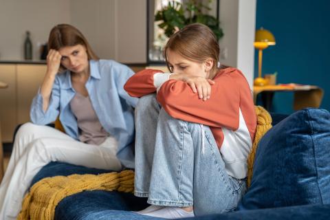 Teen girl upset with mom on couch.