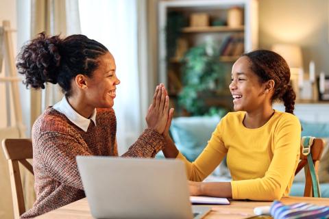 Woman helping young girl with her homework.