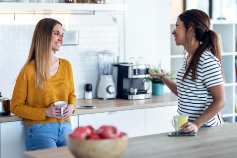 Two women talking in kitchen.