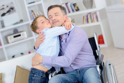 Dad in wheelchair hugging son.