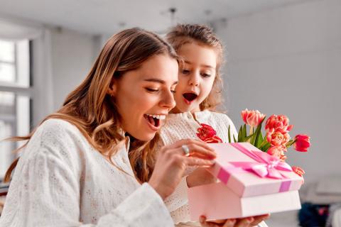 Mom and little girl opening a present, smiling.
