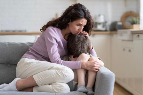 Mom comforting son on the couch.