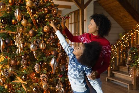 Mother and young daughter hanging ornaments on a Christmas tree