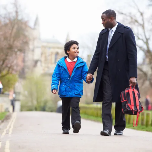 Father holds his sons hand while walking him to school