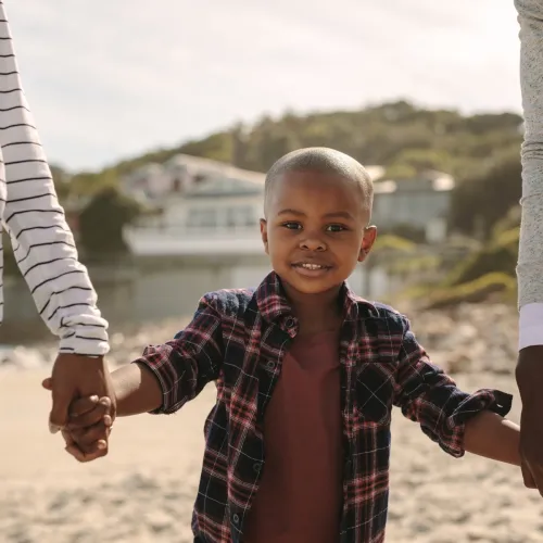A boy holds the hands of his parents.