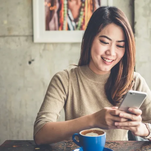 Woman looks at her phone over coffee. 