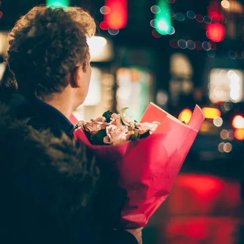 Man carries a bouquet of flowers on the street. 