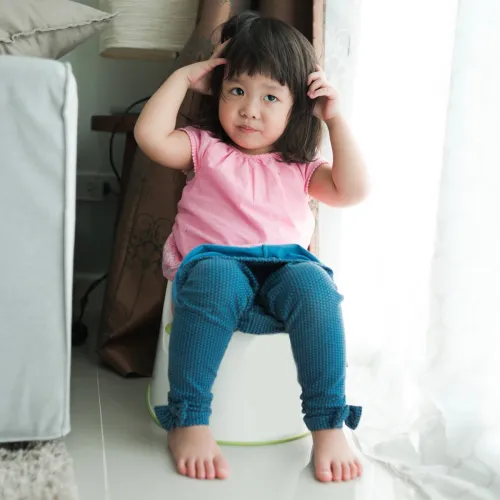 Young girl sits on a potty training toilet.