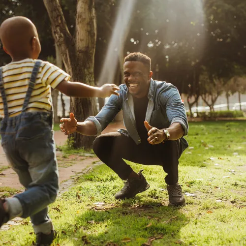 Young boy runs into his smiling father's arms on a clear spring day
