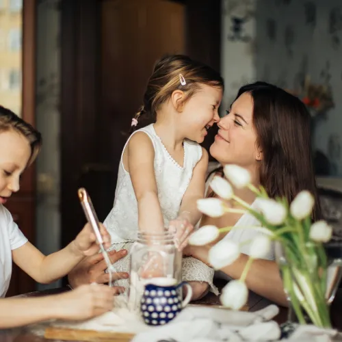 A mother shares a loving moment with her kids at the table.