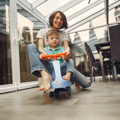 A mother and child ride a small bike together at home.