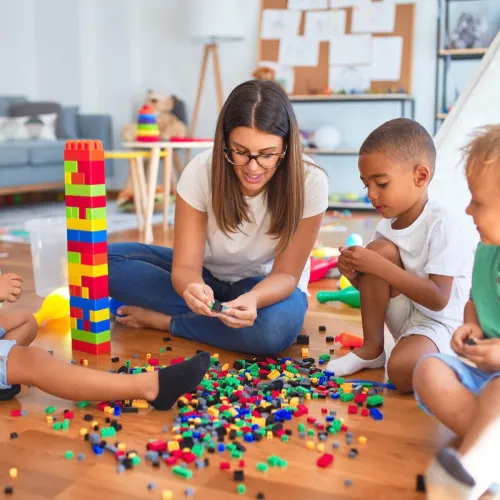 A group of young boys play with Legos with their female nanny.