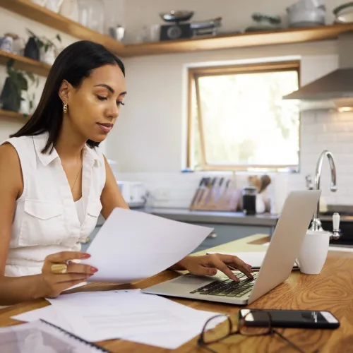 Woman on computer in kitchen. 