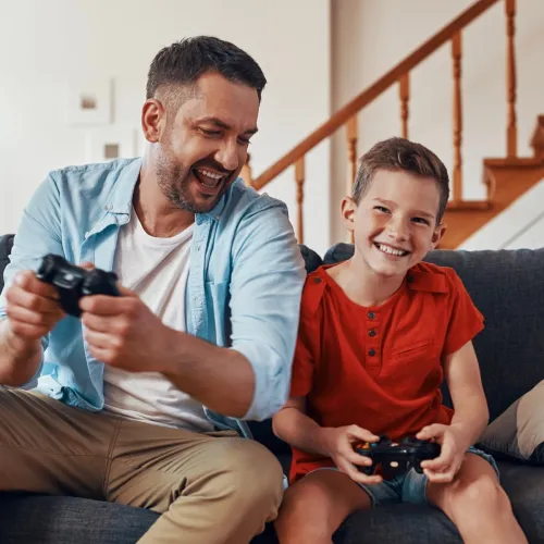 Man and son playing video games on couch. 