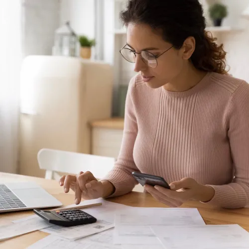 Woman uses a calculator while calculating bills and taxes