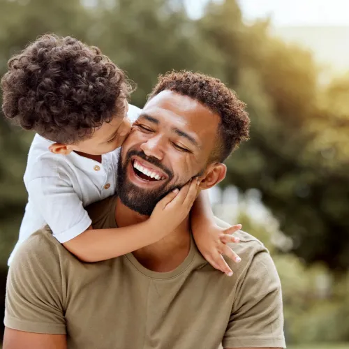 Dad giving son piggyback ride. 