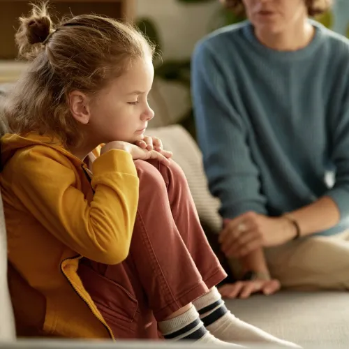 Boy sitting on couch not listening to his mom. 