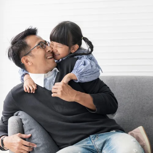 Daughter hugging her dad on couch.